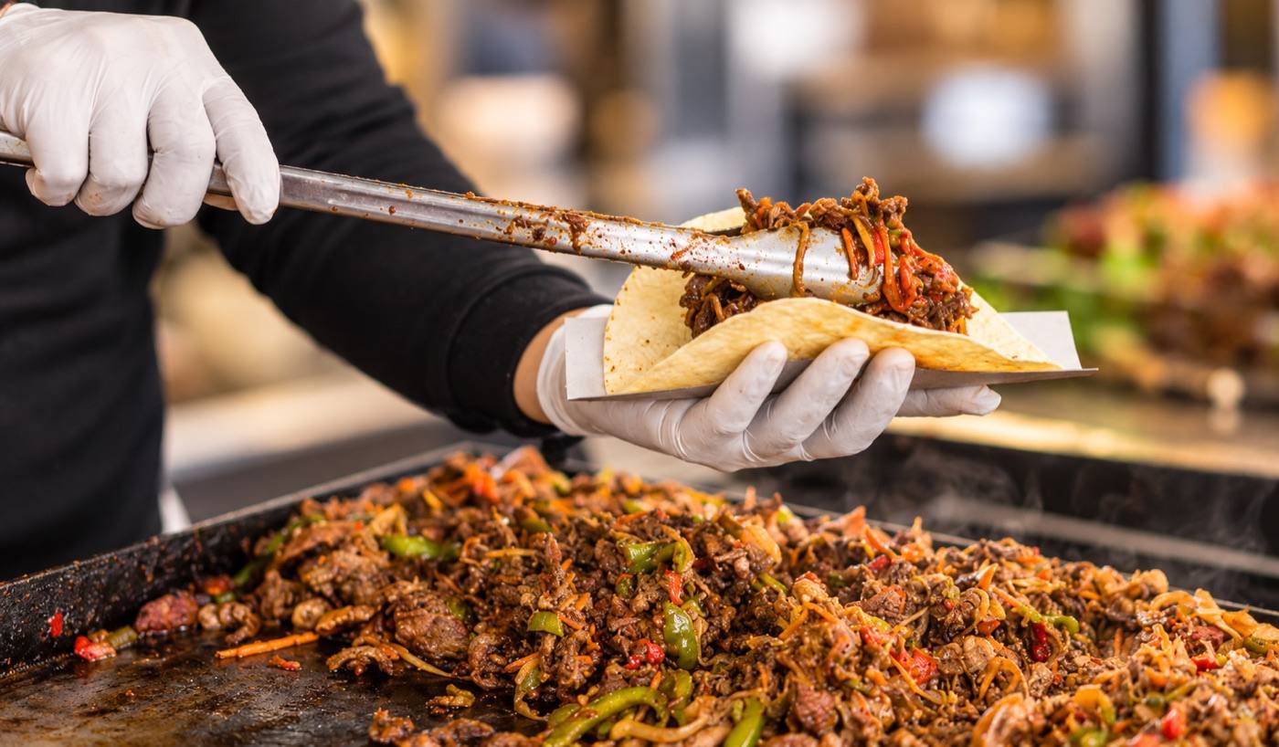 La Cocina cook serving tacos from the grill